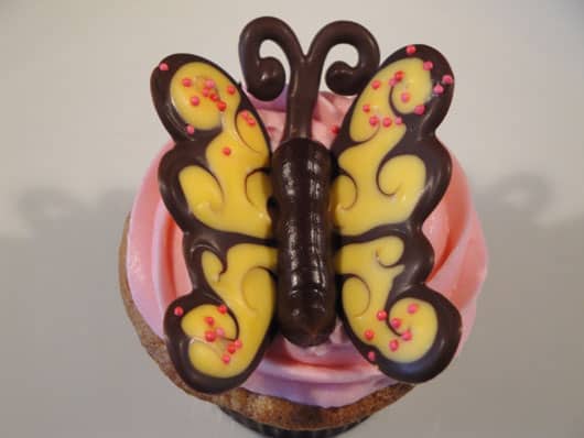 a yellow chocolate butterfly on a pink cupcake