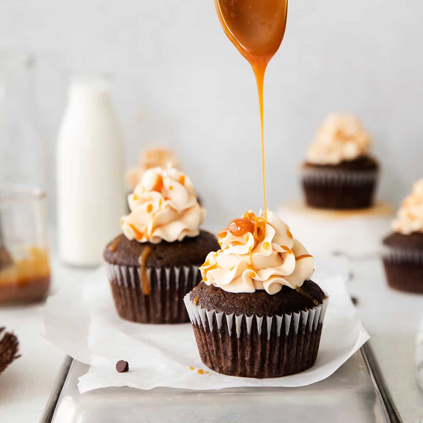 Caramel being drizzled on top of frosted chocolate cupcakes
