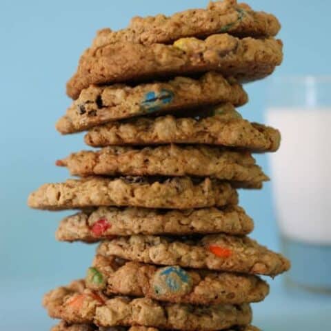 A stack of peanut butter monster cookies in front of a glass of milk.