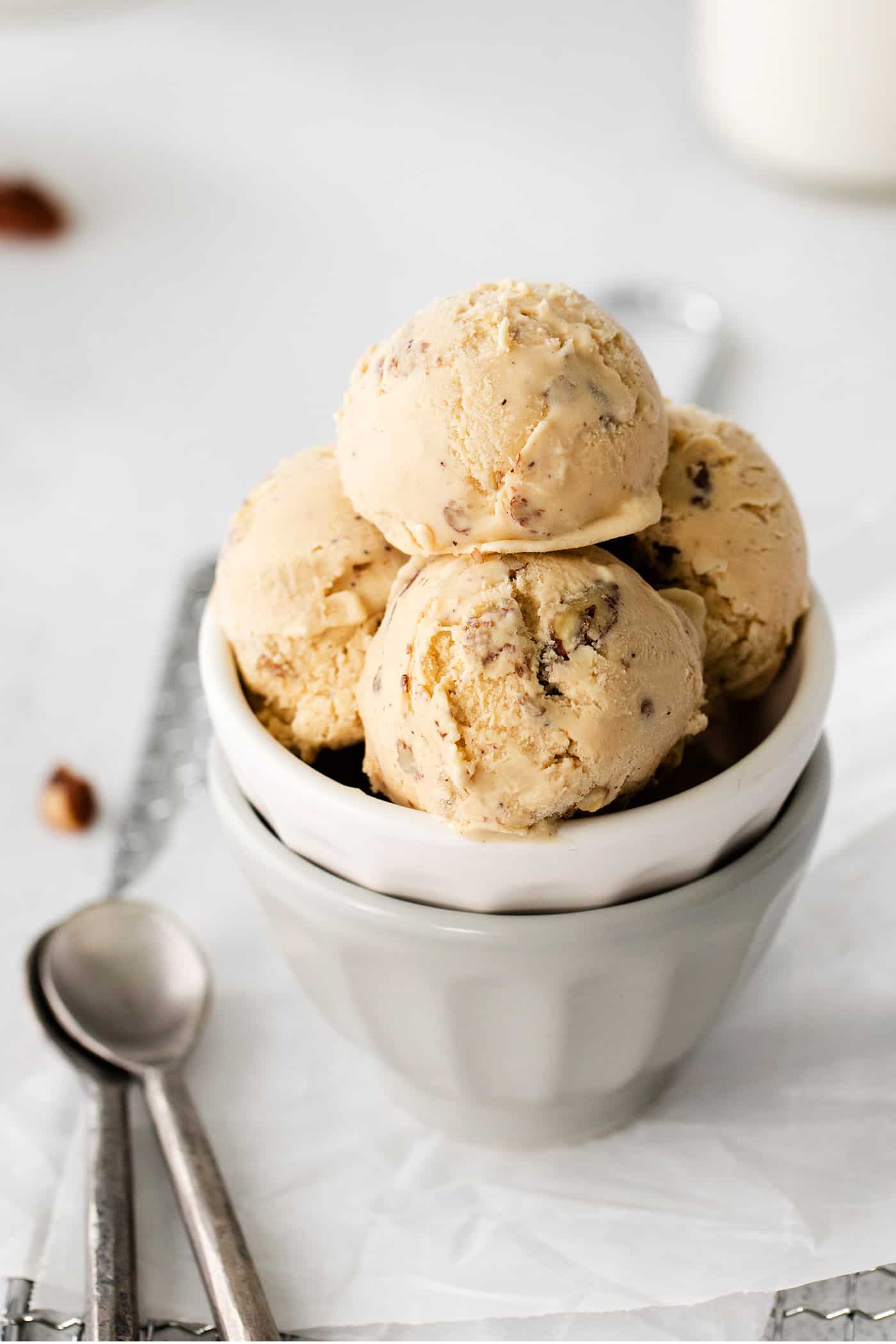 Four scoops of butter pecan ice cream next to a spoon