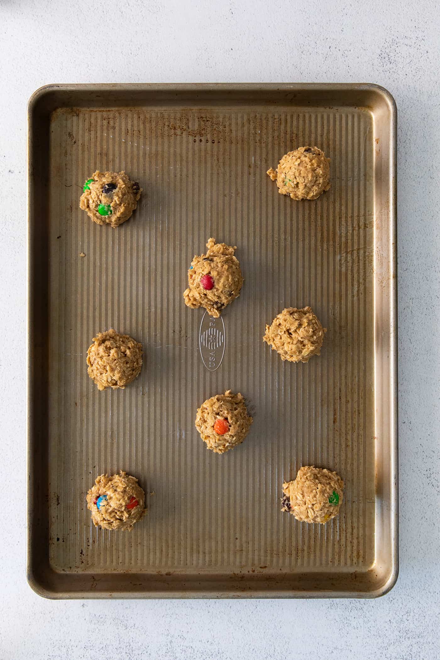 Balls of monster cookie dough on a baking sheet