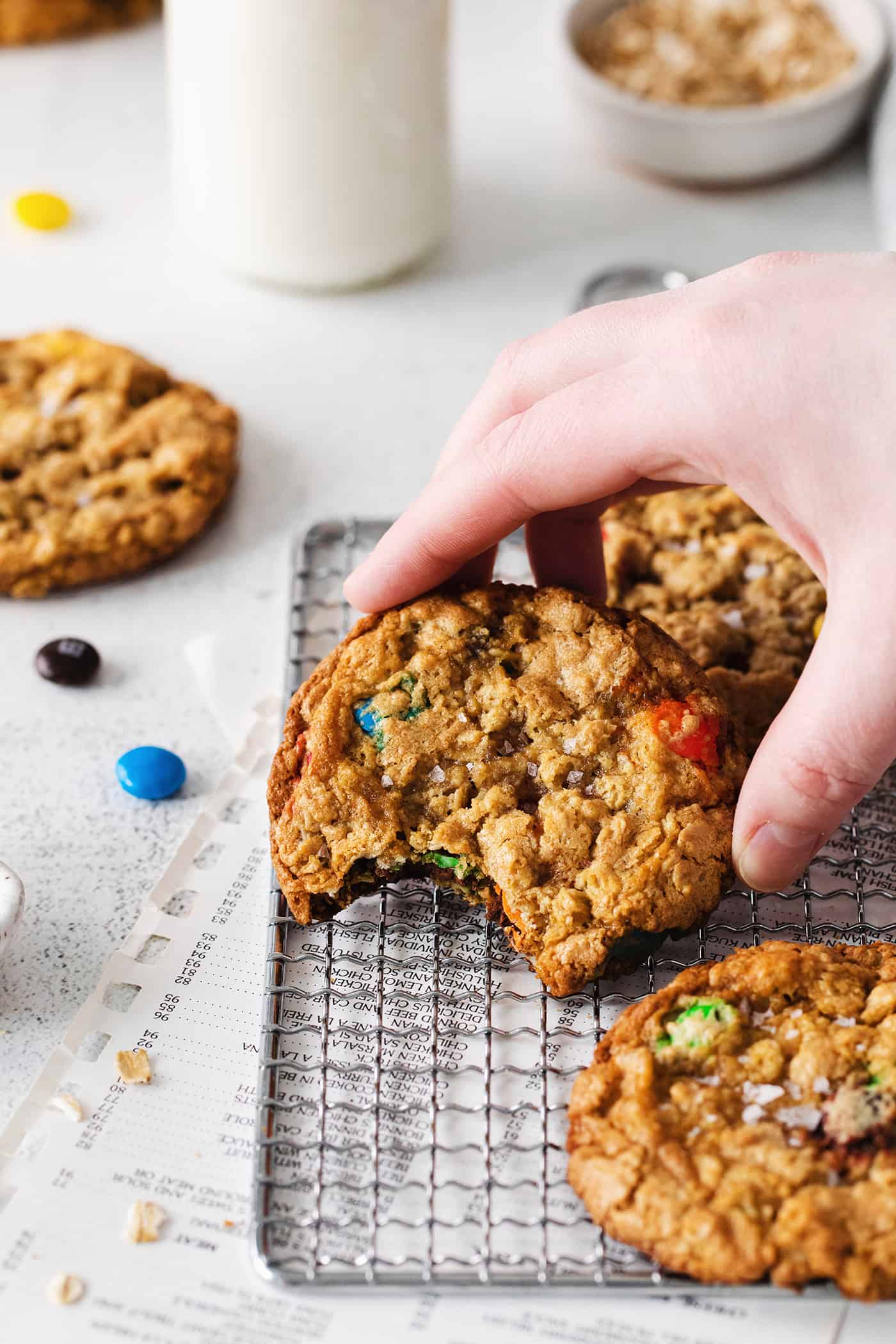 A hand holding a monster cookie with a bite missing