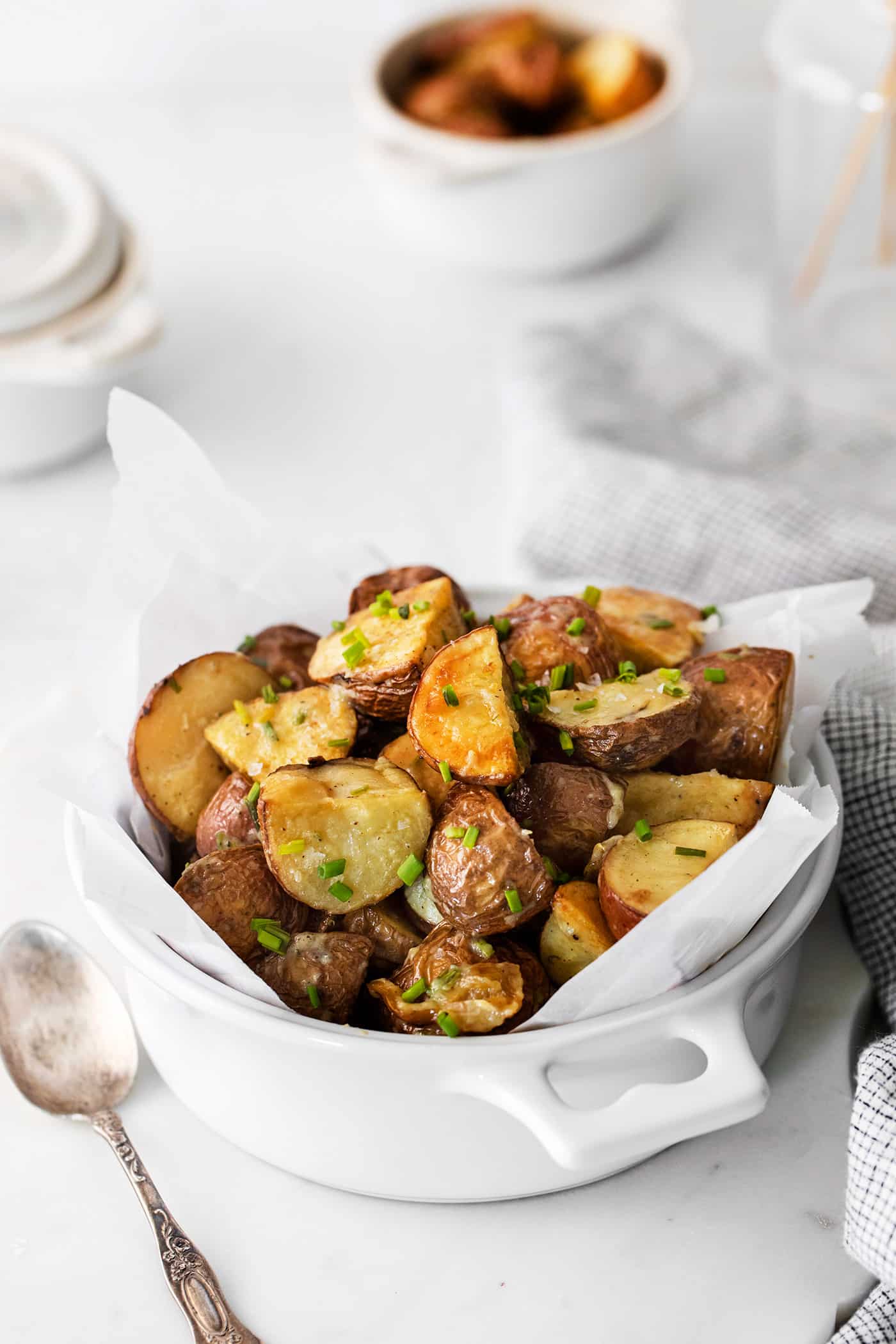 Angled view of roasted garlic new potatoes in a white bowl