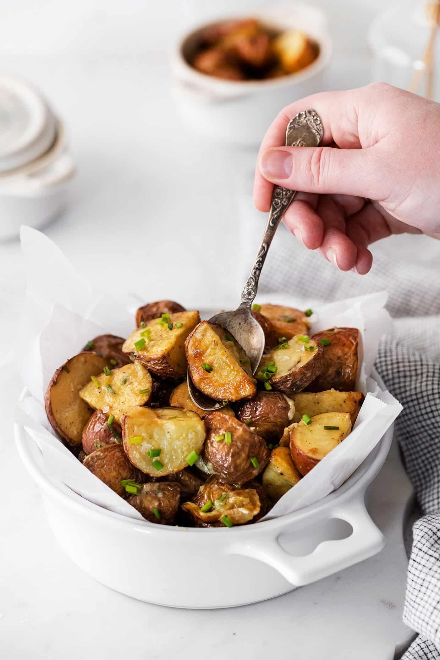 A spoon digging into a bowl of roasted garlic new potatoes