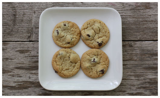 Top view of four chocolate chip cookies on a white square plate