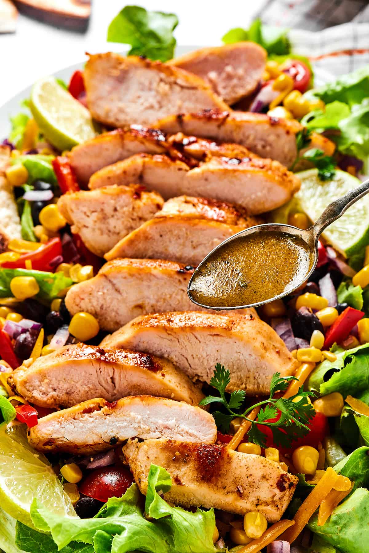 A spoon of vinaigrette being drizzled over southwest salad