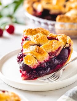 A slice of cherry pie on a white plate