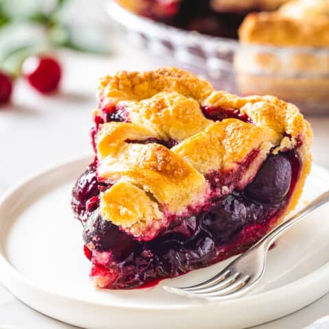 A slice of cherry pie on a white plate