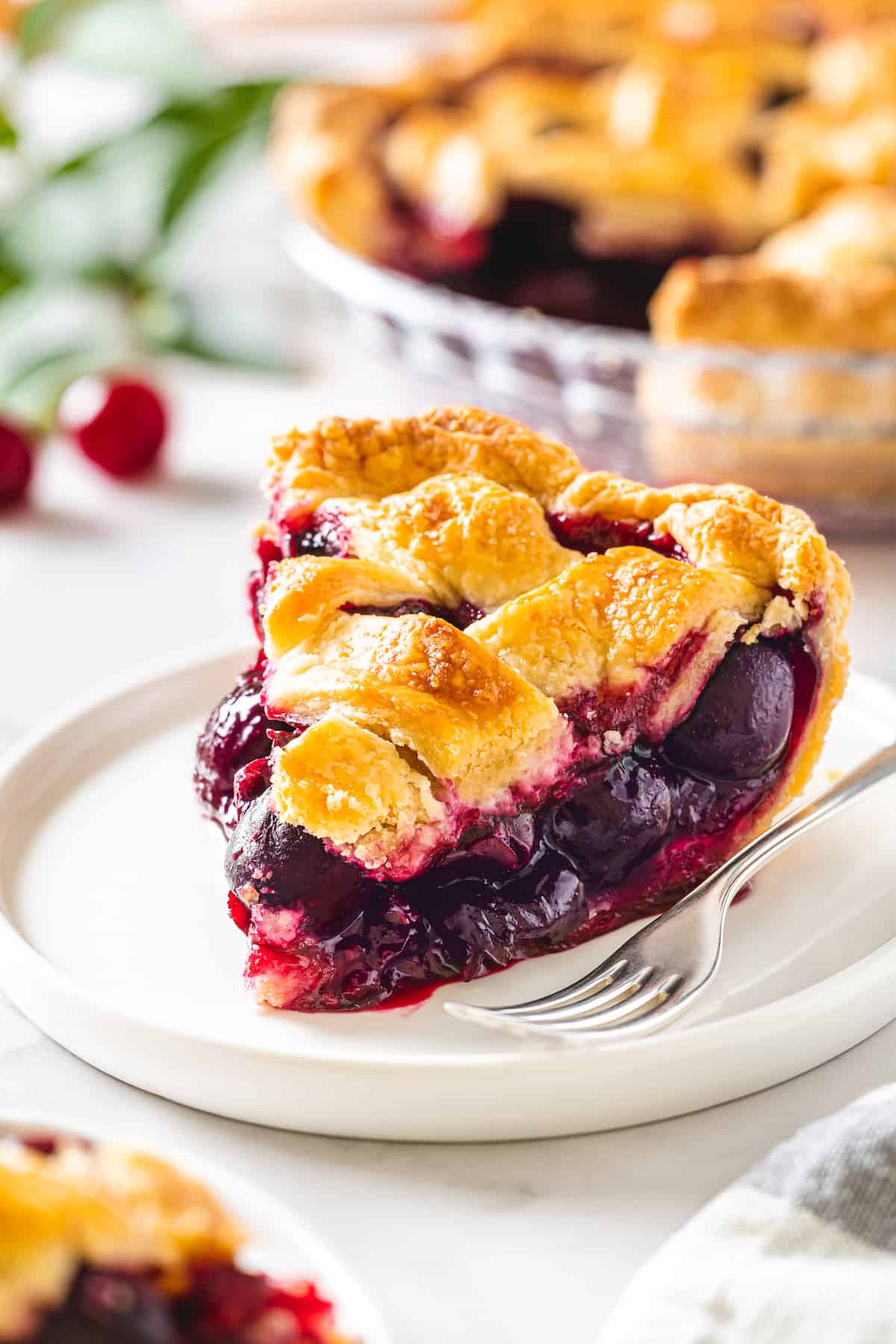 A slice of cherry pie on a white plate