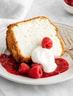 A slice of angel food cake with raspberry sauce and whipped cream