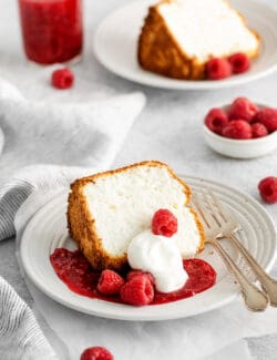 A slice of angel food cake with raspberry sauce and whipped cream