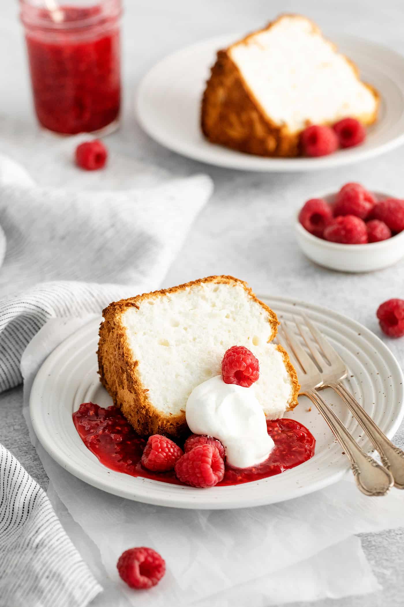 A slice of angel food cake with raspberry sauce and whipped cream