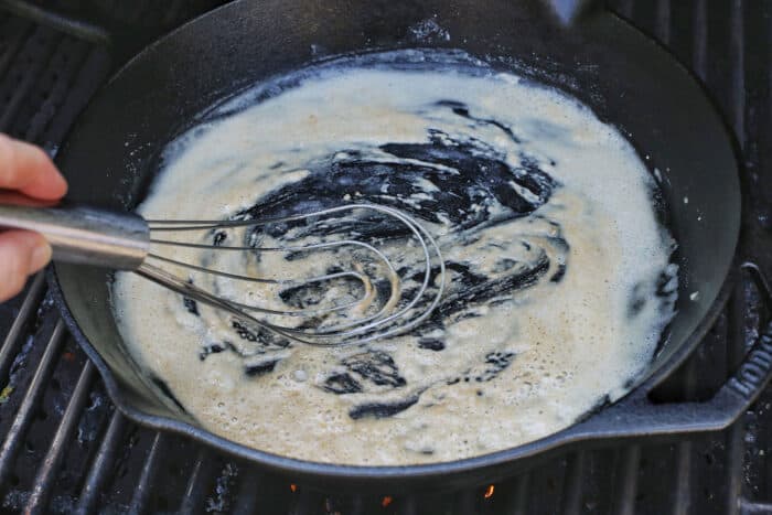Flour being whisked in butter in a cast iron skillet