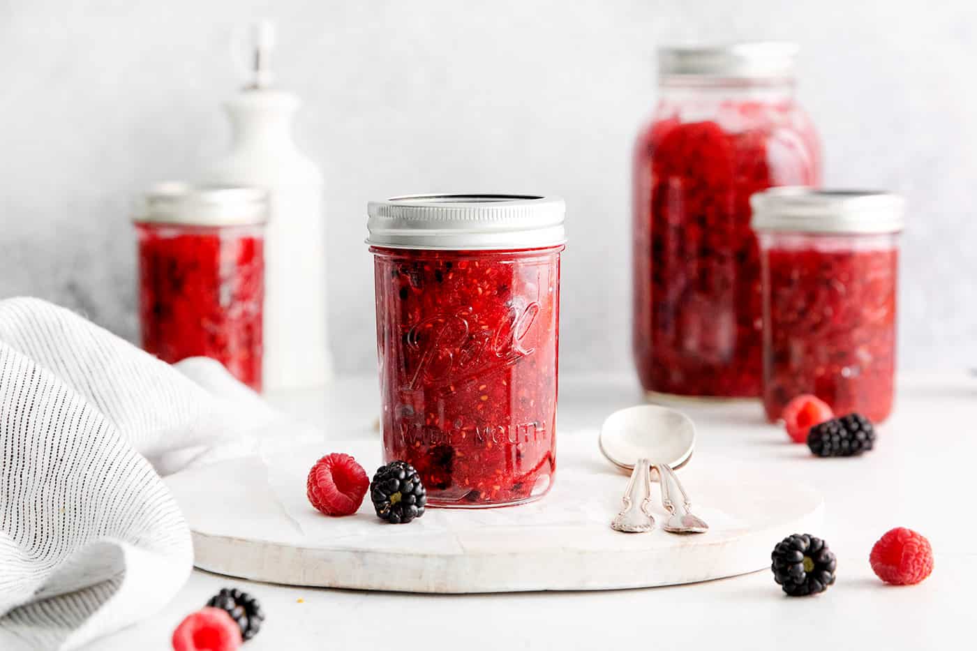 A jar of raspberry freezer jam on a white plate