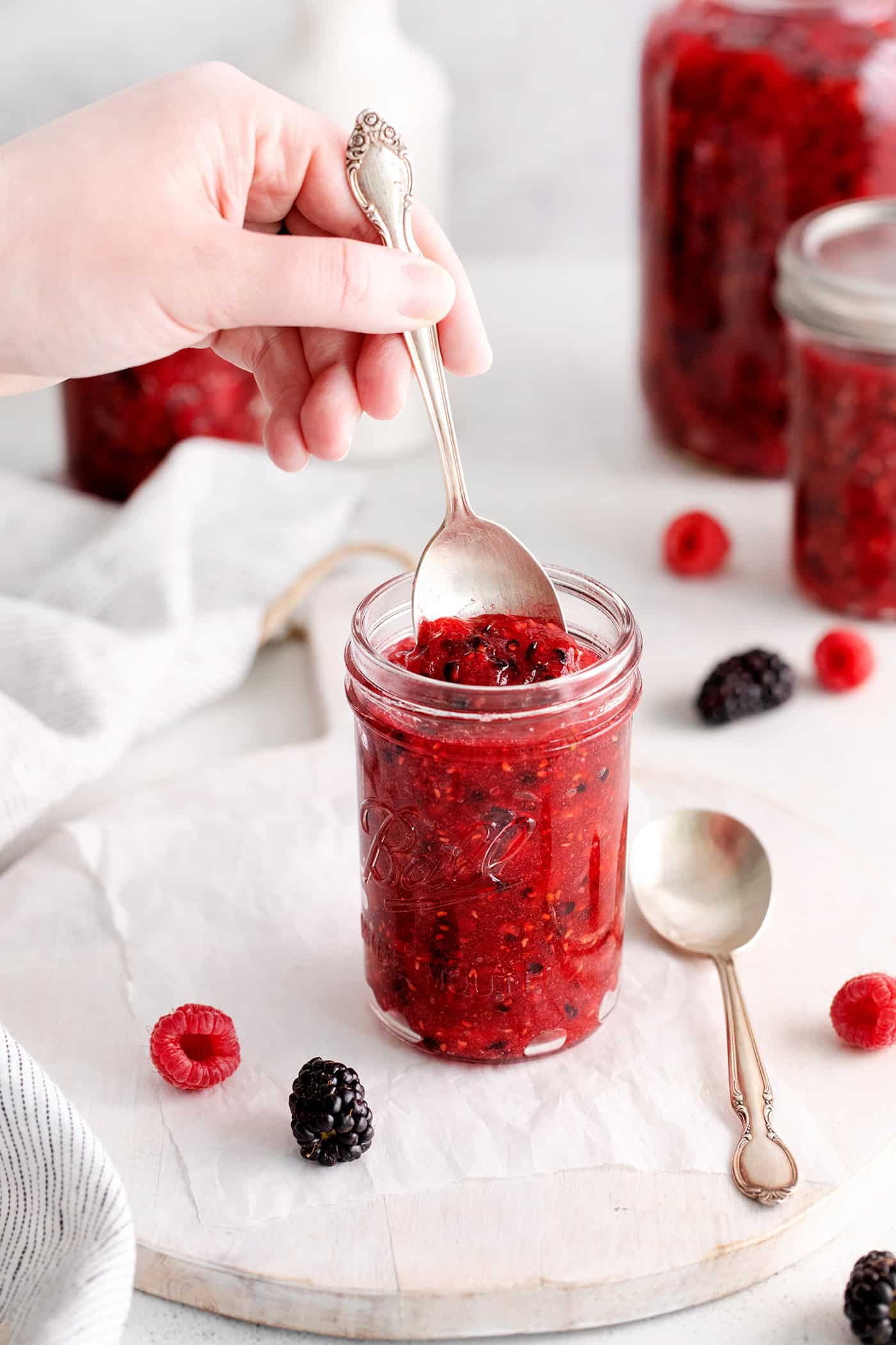 A hand with a spoon in raspberry blackberry freezer jam