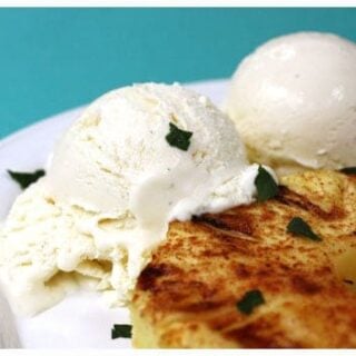 a grilled piece of pineapple with two scoops of coconut ice cream