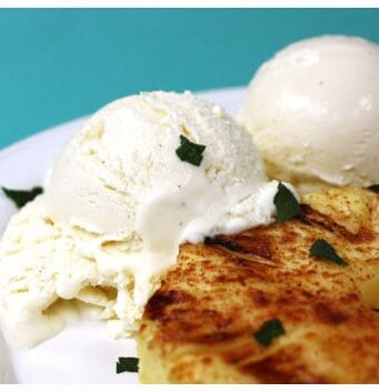 a grilled piece of pineapple with two scoops of coconut ice cream