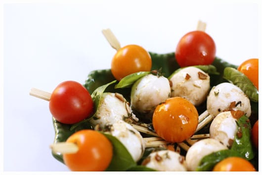 a green plate of caprese kebabs