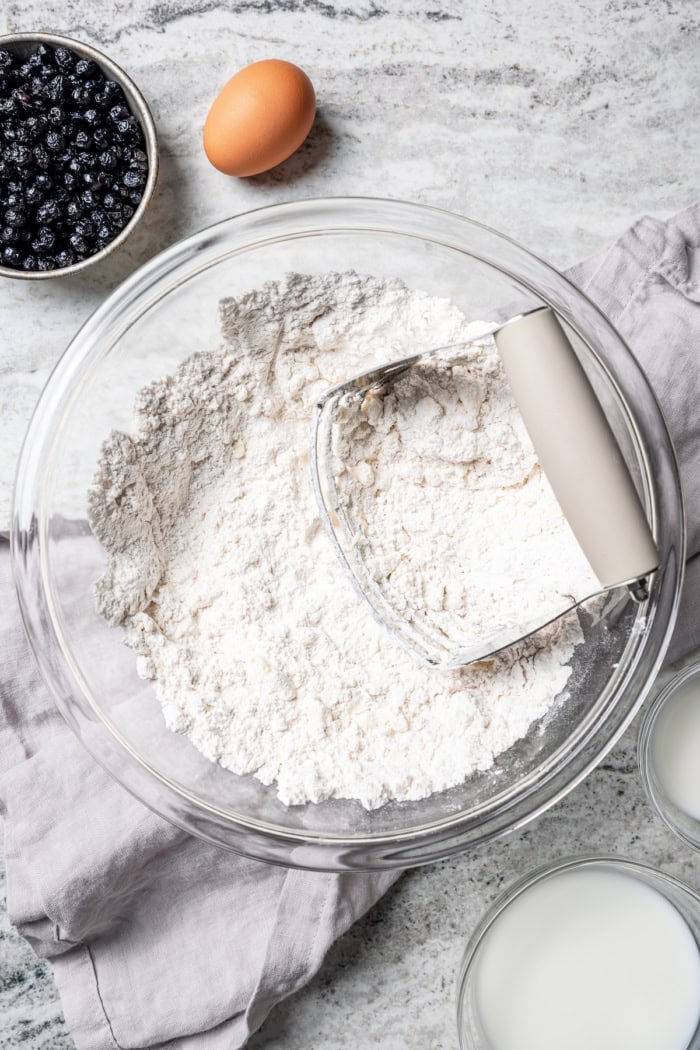 Overhead view of pastry blender in bowl with dry ingredients and butter