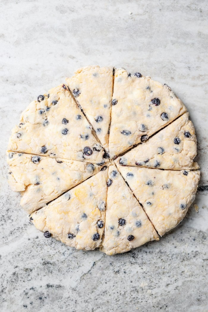 Overhead view of blueberry scones cut into wedges before baking