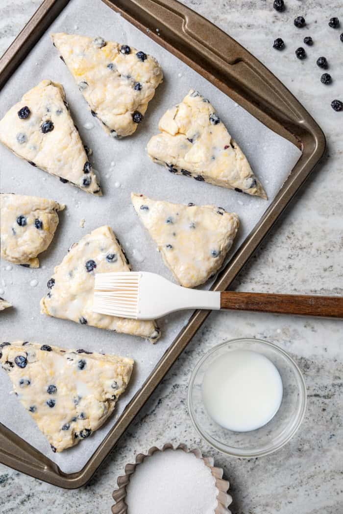 Brushing milk onto unbaked blueberry scones