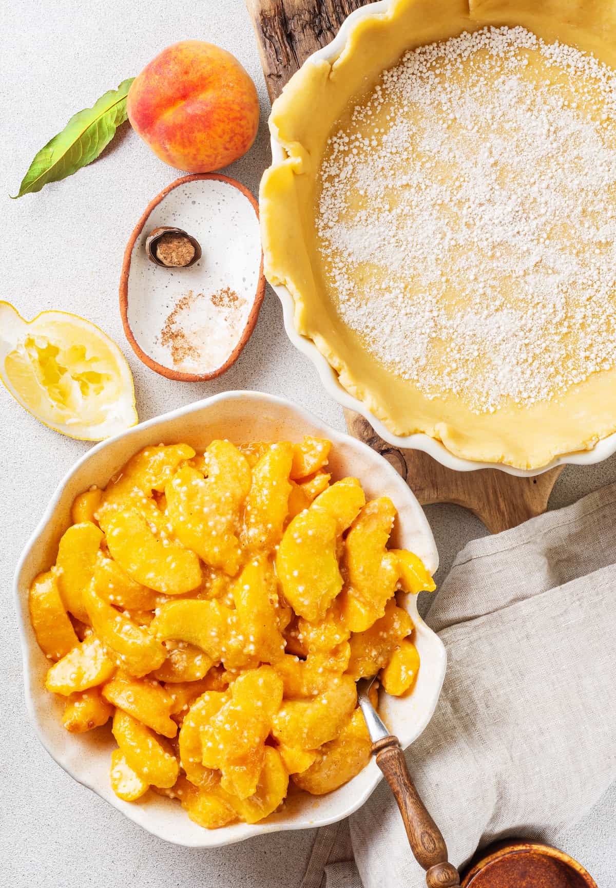 A bowl of peach pie filling next to a pie crust