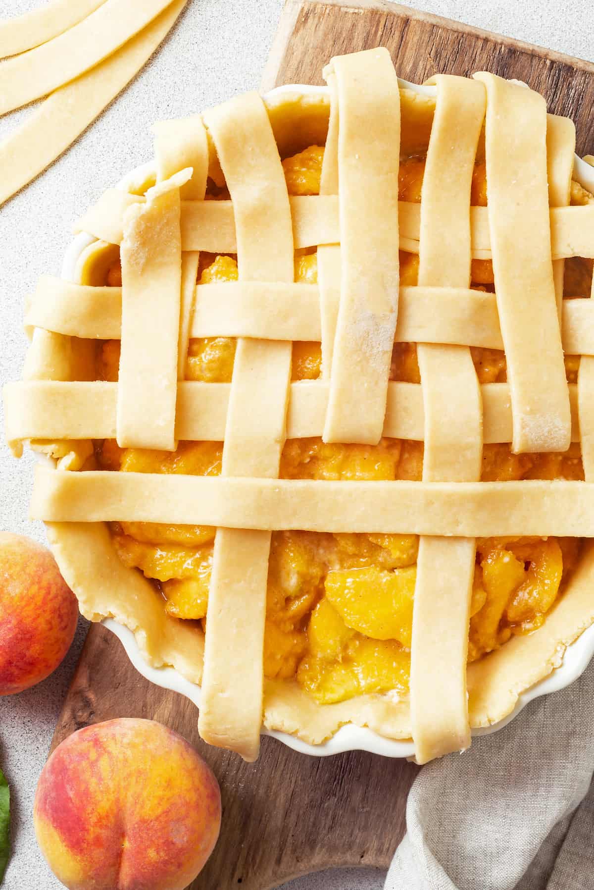 A homemade peach pie with a half-finished lattice crust