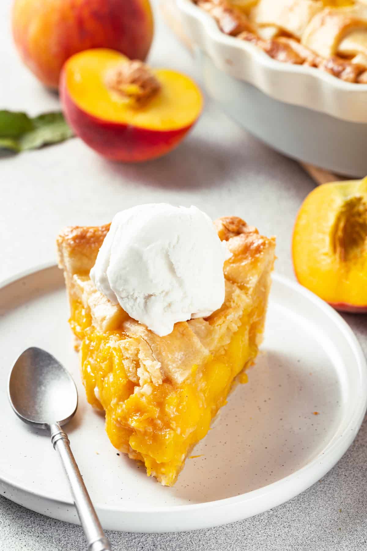 A slice of peach pie topped with a scoop of ice cream