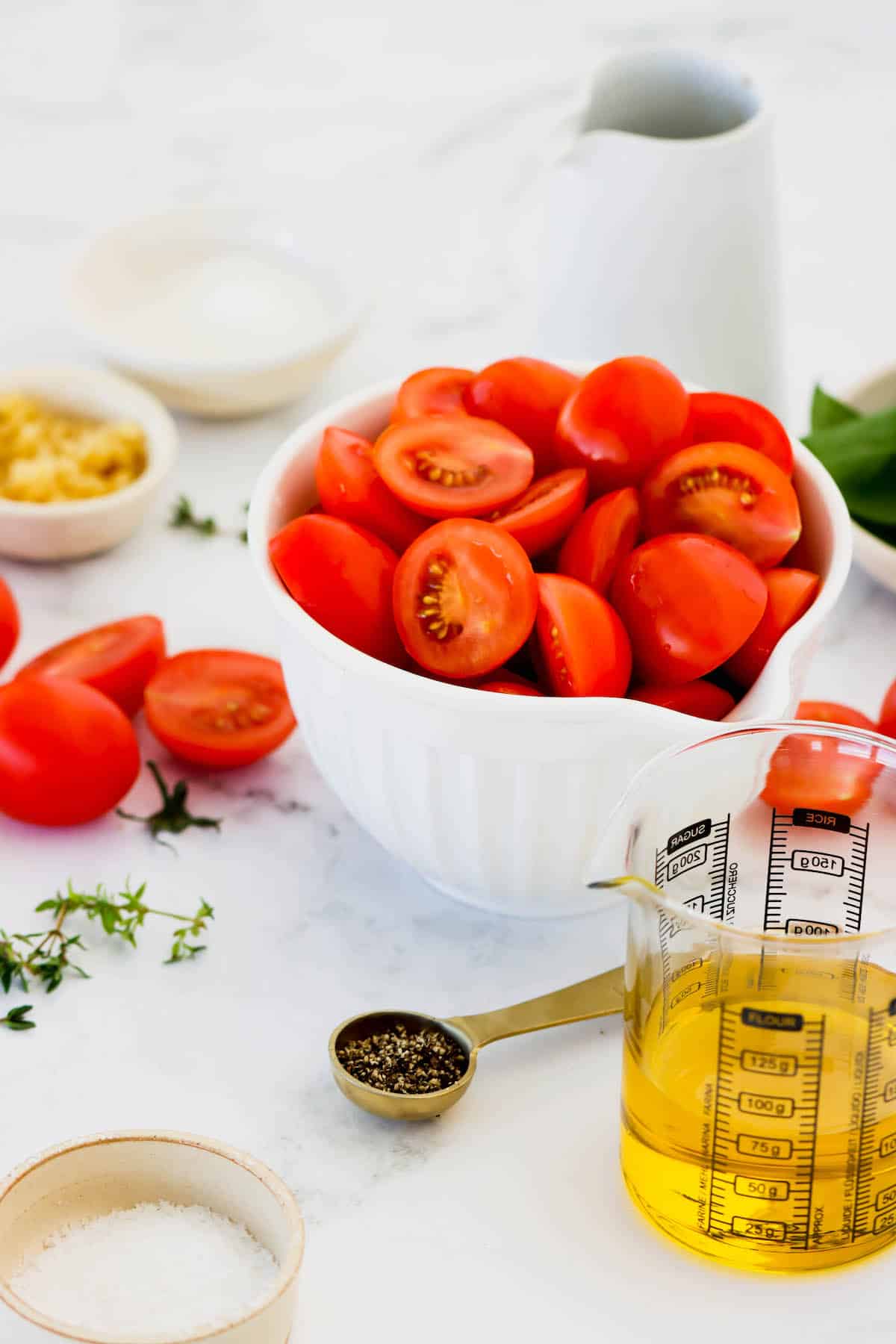 A white bowl of halved plum tomatoes