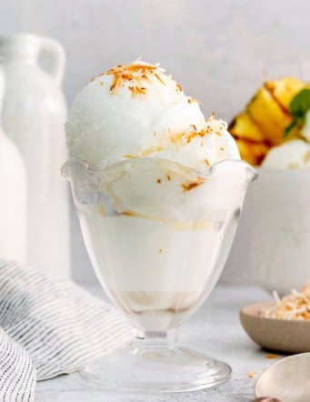 Coconut ice cream in glass dish with toasted coconut on top