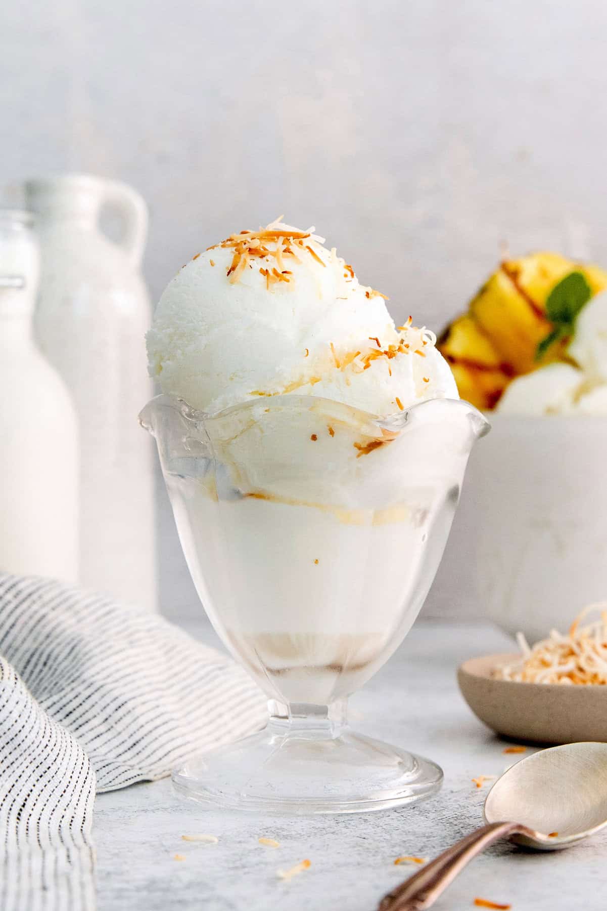Coconut ice cream in glass dish with toasted coconut on top