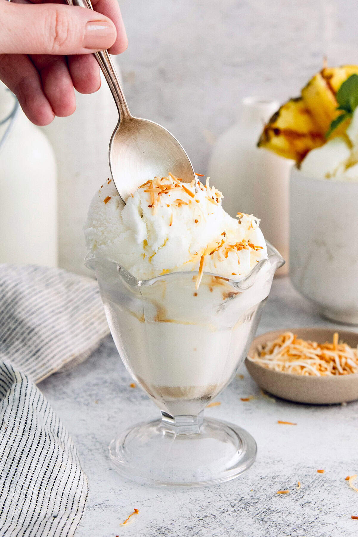 Spoon digging into coconut ice cream topped with toasted coconut