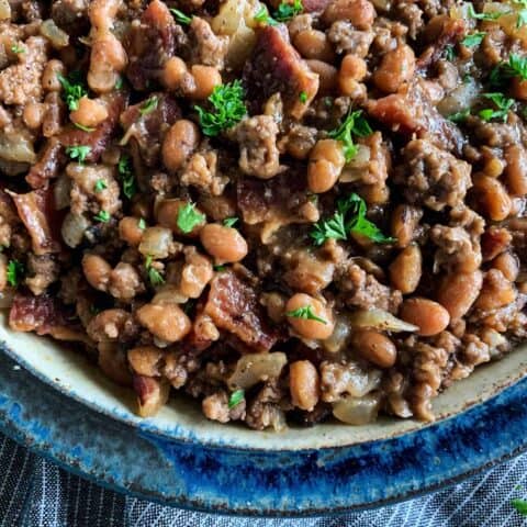 a bowl of baked beans with bacon and ground beef