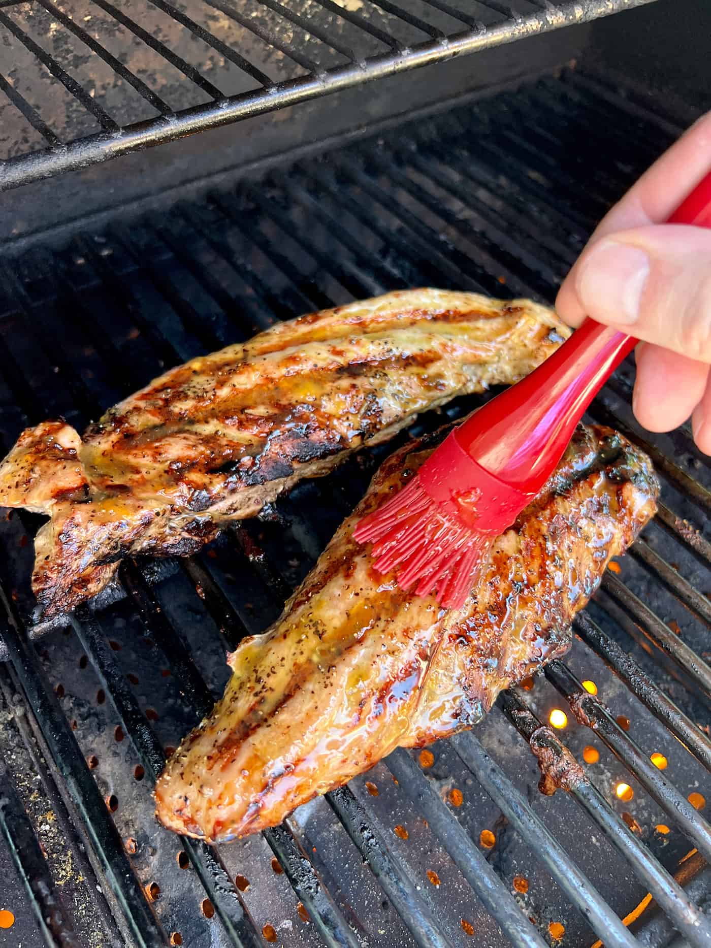 Brushing peach glaze on pork tenderloins