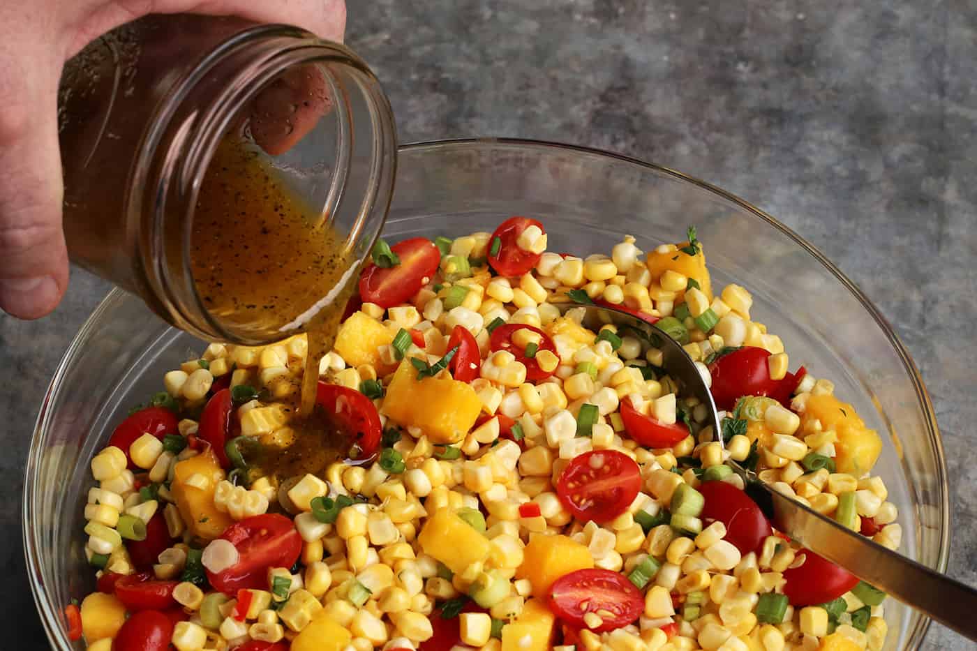 Vinaigrette being poured over sweet corn salad