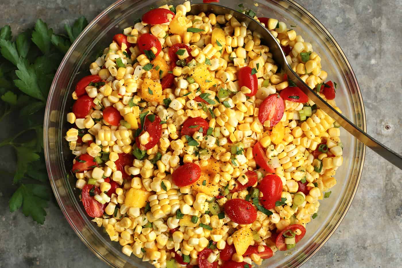 Sweet corn salad with tomato and mango in a glass bowl