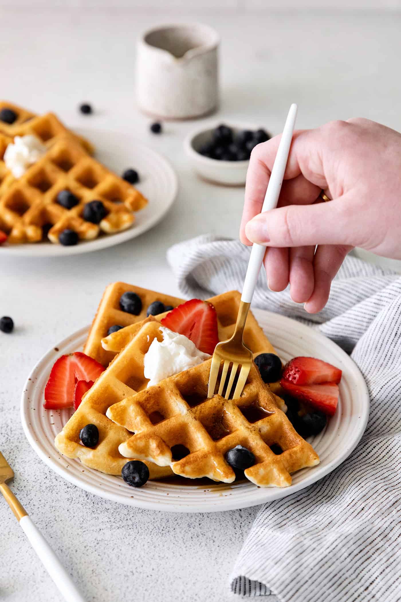 A fork diving into a plate of waffles