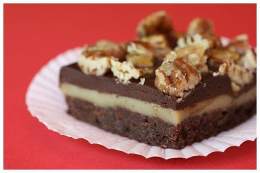 a layered brownie topped with chopped pecans