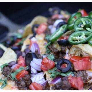ground beef, onions, tomatoes, olives, jalapeños, and cheese on tortilla chips