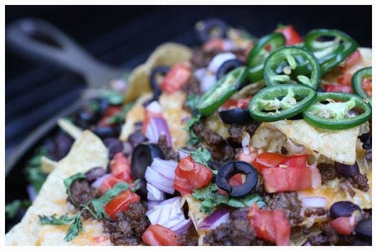 ground beef, onions, tomatoes, olives, jalapeños, and cheese on tortilla chips