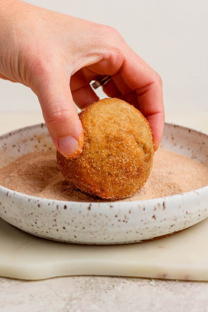 Cinnamon sugar doughnut muffins are easy to make and impossible to resist, with a moist, tender crumb and lots of cozy flavor. Perfection! Dipping doughnut muffin into shallow bowl of cinnamon sugar