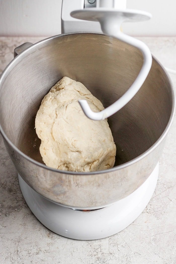 This Grilled Pizza recipe is tested and perfected, with a homemade dough that doesn't fall through the grates. Smoky, crispy, and delicious! Pizza dough in stand mixer bowl with dough hook.