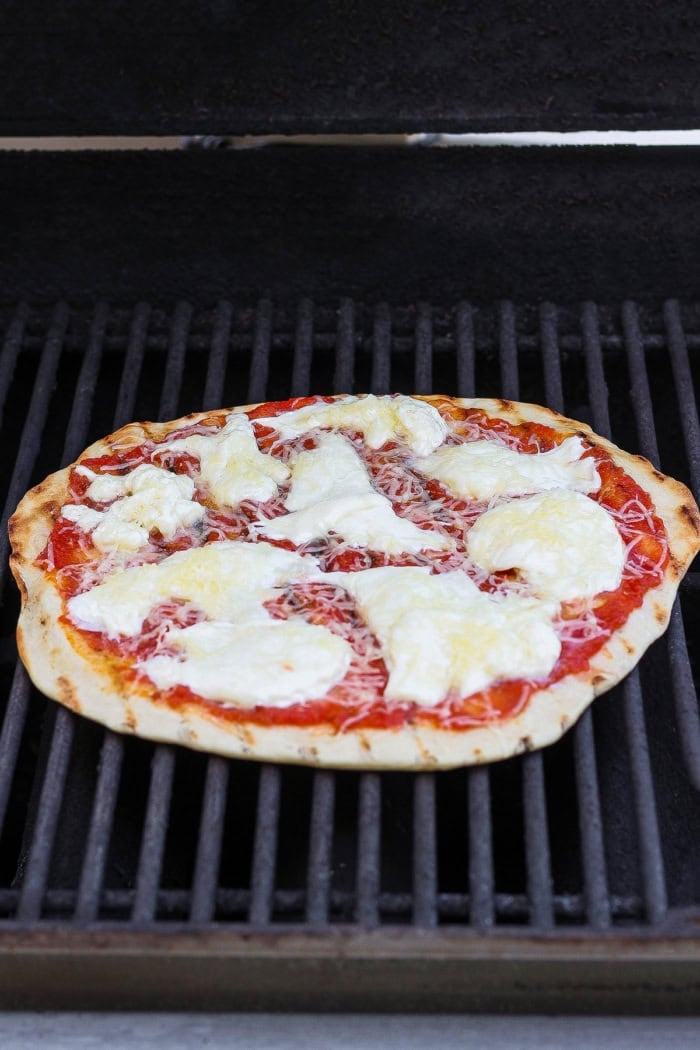 Margherita pizza cooking on grill.