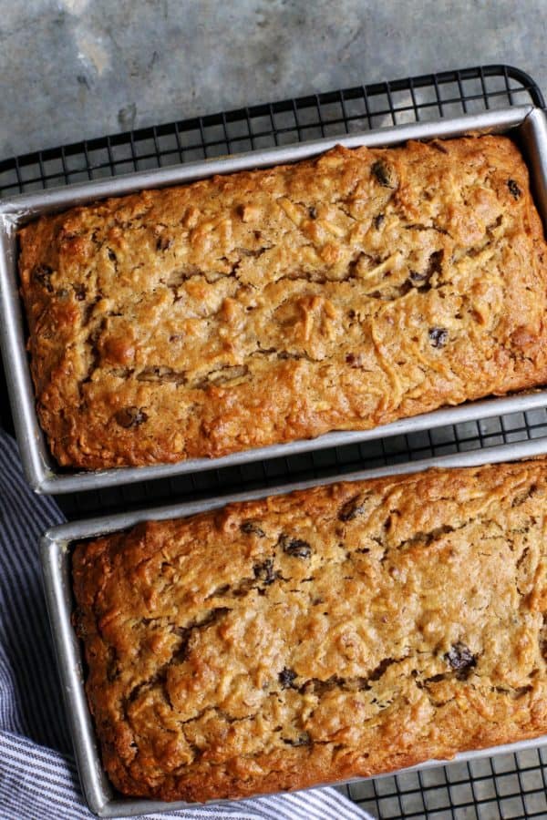 two loaves of apple bread in pans on cooling rack