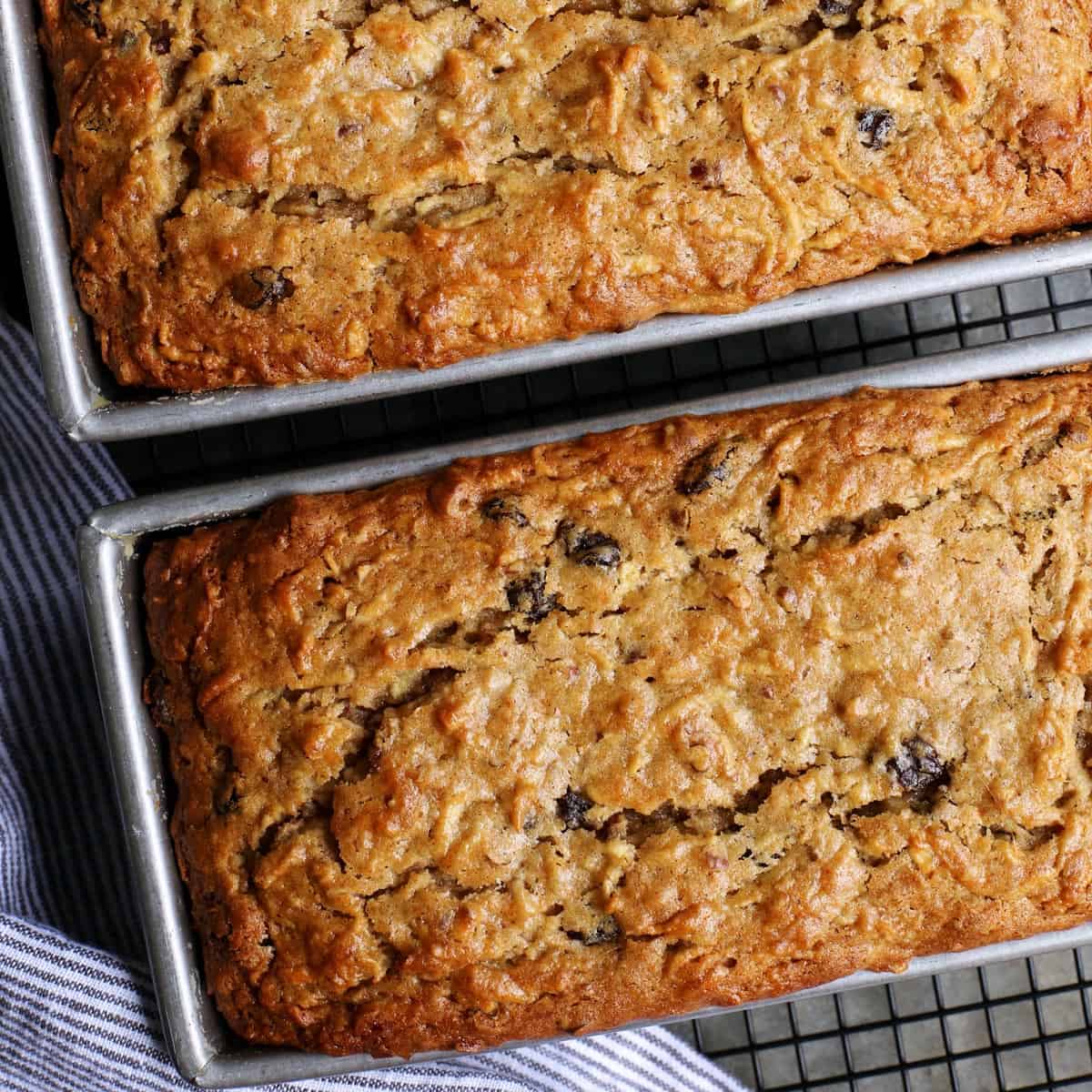 two loaves of apple bread in pans on cooling rack