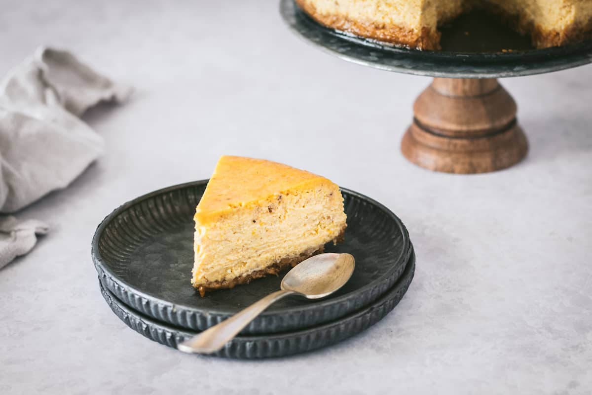 A slice of pumpkin cheesecake on a black plate