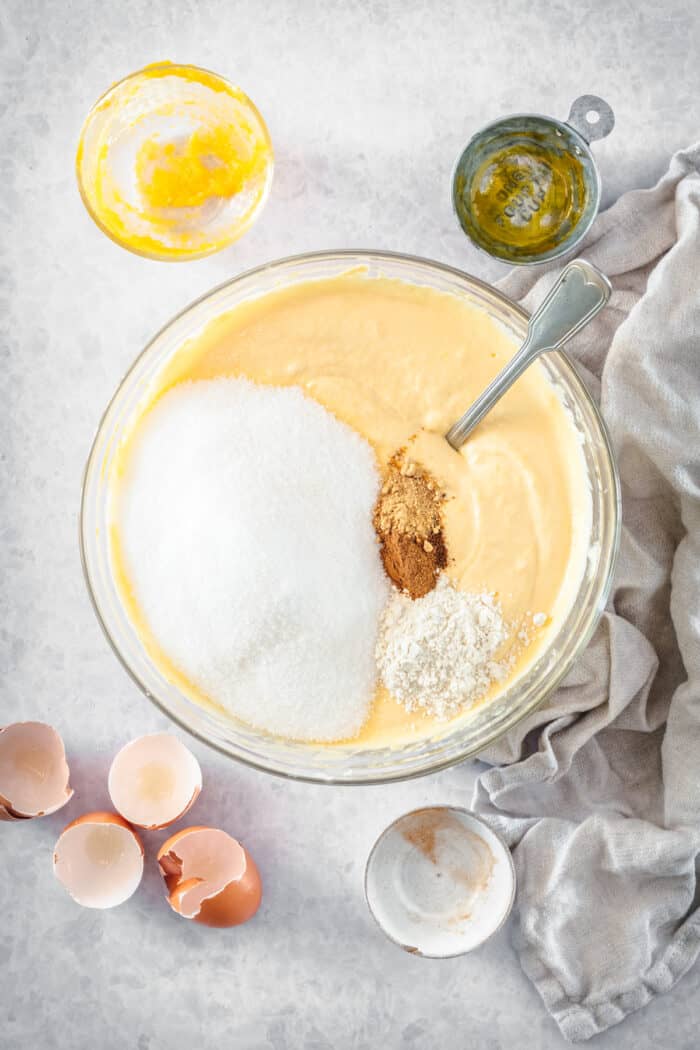 Sugar and spices added pumpkin cheesecake batter in a mixing bowl.