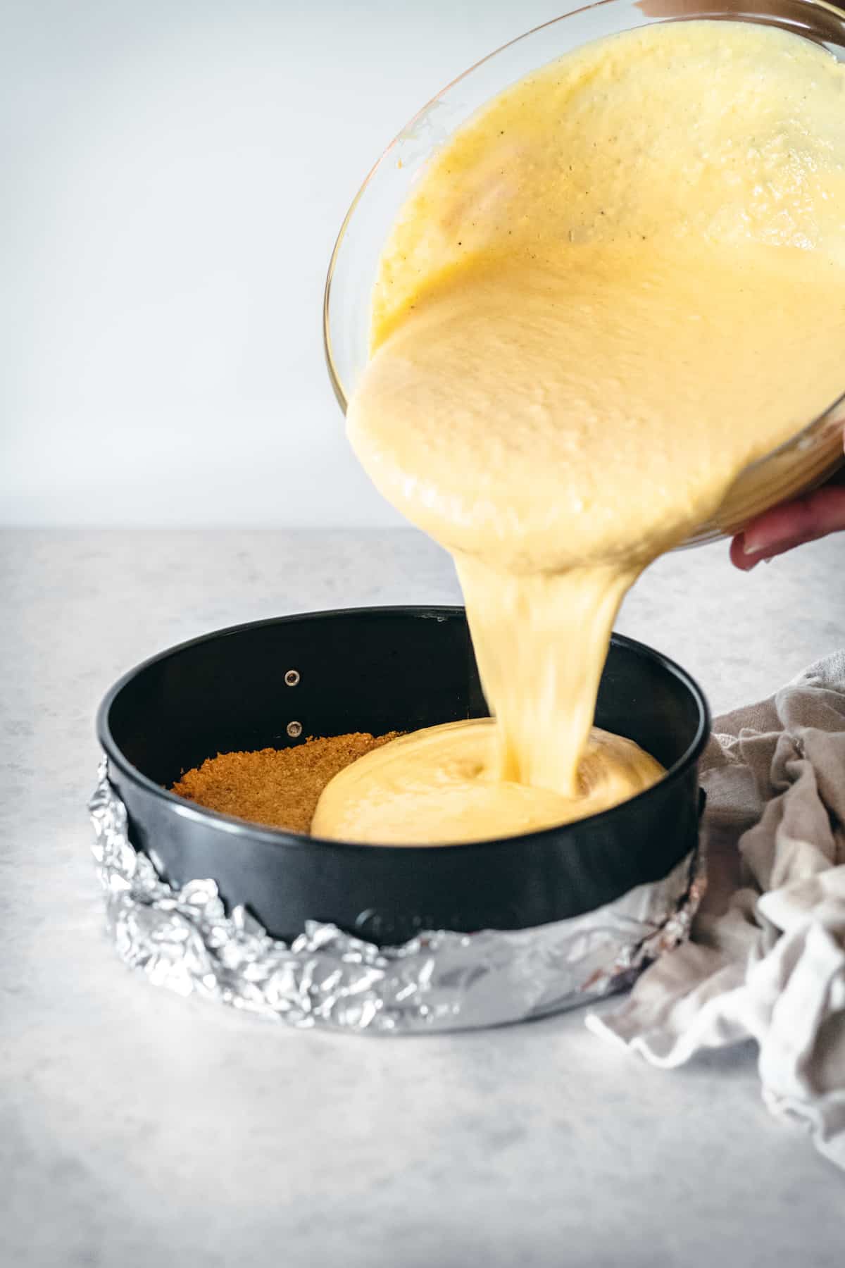 Pumpkin cheesecake batter being poured into a springform pan