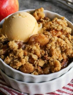 Homemade apple crisp in a white ramekin with a scoop of ice cream