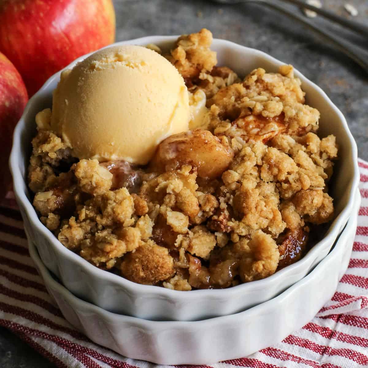 Homemade apple crisp in a white ramekin with a scoop of ice cream